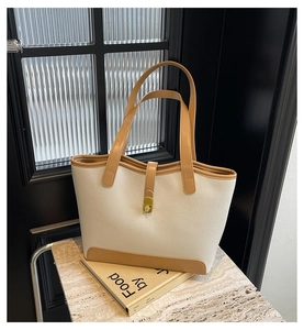 Detailed close-up of textured lychee grain leather and gold metal buckle on tote bag