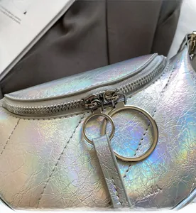 Détail du sac selle holographique argenté avec double zip à anneaux et texture ondulée