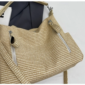Detailed close-up of woven tote bag texture featuring silver zipper and wide strap
