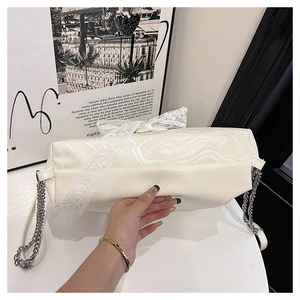 Detail of cream tote bag featuring marble texture panels and white lace bow accessory