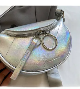 Gros plan d'un sac demi-lune argent holographique avec texture froissée et zip double