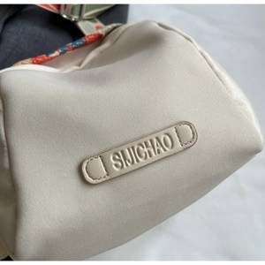 Detail of canvas bag with brand logo and colorful floral jacquard shoulder strap