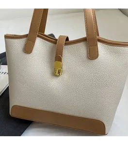 Detail of lychee textured canvas tote bag with contrast trim and golden swivel lock