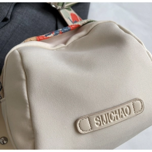 Close-up of canvas shell bag with colorful woven strap and leather logo patch