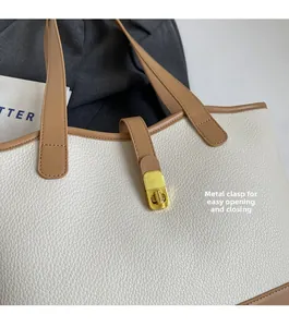 Detailed view of large white tote bag featuring a golden hardware lock and lychee texture