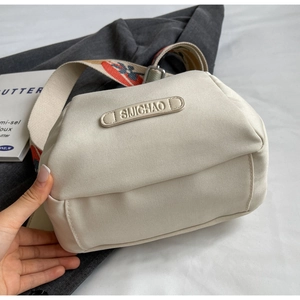 Detail of off-white canvas crossbody bag with ethnic pattern wide strap and logo tag