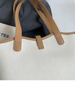 Macro shot of precise stitching and magnetic closure on white lychee leather tote bag