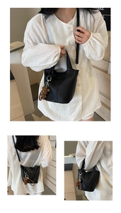 Detail of black lychee grain leather bucket bag with a cute checkered bear charm accessory