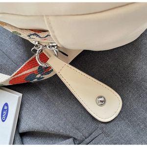 Detail of canvas shell bag with colorful jacquard strap and silver metal hardware