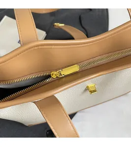 Close-up of golden zipper hardware and lychee pattern leather texture on a tote bag