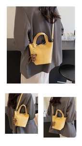 Detail of yellow lychee textured bucket bag with cute bear charm and adjustable strap