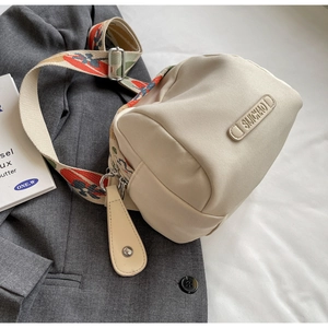 Detail of beige canvas shell bag with colorful jacquard strap on grey blazer fabric