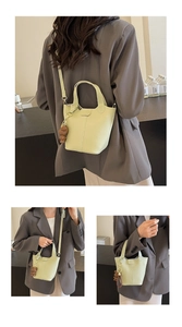 Detail of light green bucket bag with lychee texture and a cute bear bag charm