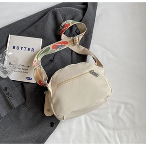 Detail of off-white canvas shell bag with colorful tulip jacquard strap and back zip pocket