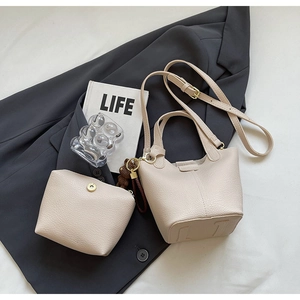 Detail of cream white bucket bag set with pebble leather texture and bear charm