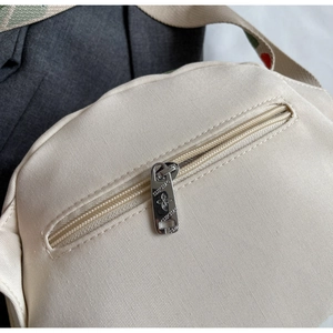 Detail of canvas crossbody bag back zipper pocket with custom floral metal puller