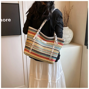 Detail of multi-color rainbow straw tote bag with silver handle and metallic rivets