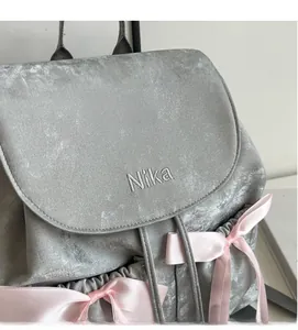 Detail view of grey chenille backpack featuring pink satin bows and Nika embroidery