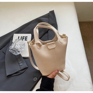 Close-up of cream bucket bag with lychee texture and pale gold hardware details