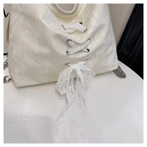 Close-up of marble texture on cream bag with white lace ribbon and silver chain detail