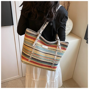 Detail of multi-color woven straw tote bag with silver leather straps and metal hardware