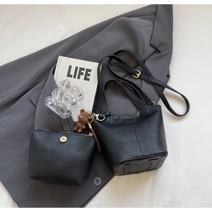Detail of black lychee grain bucket bag with teddy bear charm and inner pouch