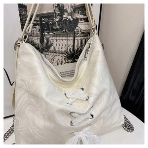 Close-up of marble pattern tote bag featuring lace bow and silver chain strap