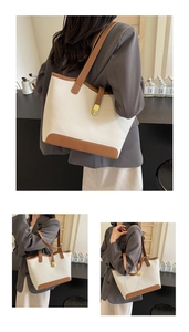 Detail of large canvas tote bag with brown leather trim and metallic buckle closure