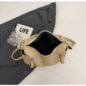 Detail view of the beige woven tote bag showing the zipper closure and black interior lining