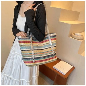 Detail of colorful woven tote bag with silver studded leather straps and logo plate