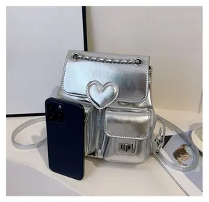 Close-up of silver mini backpack with heart buckle and chain strap shown with phone