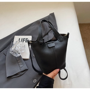 Detail of black lychee grain leather bucket bag featuring double handles and long strap