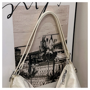 Detail showing the cream white shoulder bag with unique embossed wave texture and silver zipper