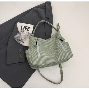 Detail of light green woven hobo bag with dual vertical zipper pockets on front