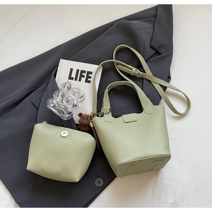 Detail of sage green lychee grain leather bucket bag with matching pouch and bear charm