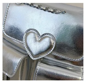 Detail of silver metallic backpack featuring heart patch and chain strap texture