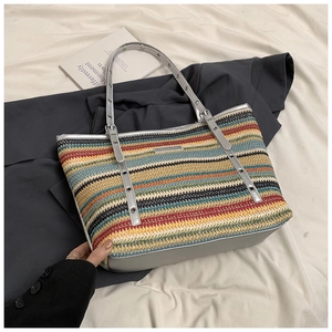 Close-up of colorful striped woven tote bag featuring shiny silver metallic handles