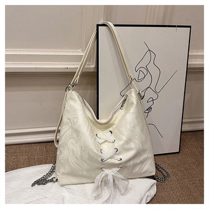 Detail view of cream shoulder bag featuring marble texture, lace bow and metal chain