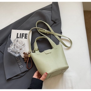 Light green pebble leather bucket bag with a detachable strap and a cute bear charm