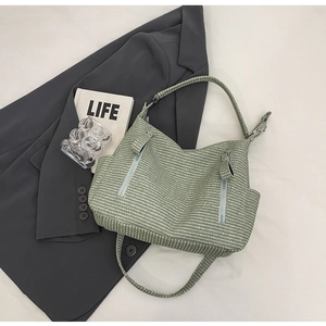 Detail of woven green hobo bag featuring vertical zippers and side pockets on fabric