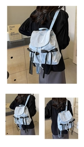 Detail of light blue satin backpack with black lace bows and Nika embroidery