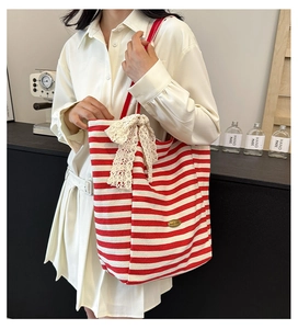 Detail of red and white striped canvas tote bag with a beige lace bow and brand logo
