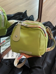 Grass green nylon shell crossbody bag featuring a floral pattern wide woven strap