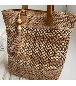 Detail of woven straw tote bag with multi-layer texture, tassels and brown leather handles