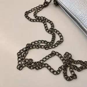 Detailaufnahme der silbernen Ledertasche mit robuster, dunkelgrauer Metallkette
