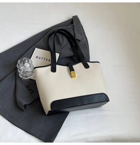 Detail of the high-quality gold metal twist lock on a minimalist cream leather tote bag