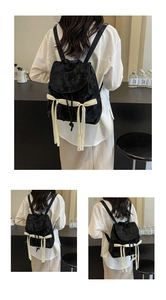 Detail showing black backpack with ribbon bow tassels and embossed brand logo