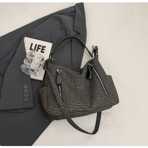 Detail view of woven tote bag with silver zippers and adjustable shoulder strap