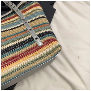 Close-up of colorful striped straw tote bag with metallic silver base and eyelet strap