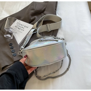 Détail du sac de selle laser argenté avec bandoulière et chaîne sur un fond esthétique urbain